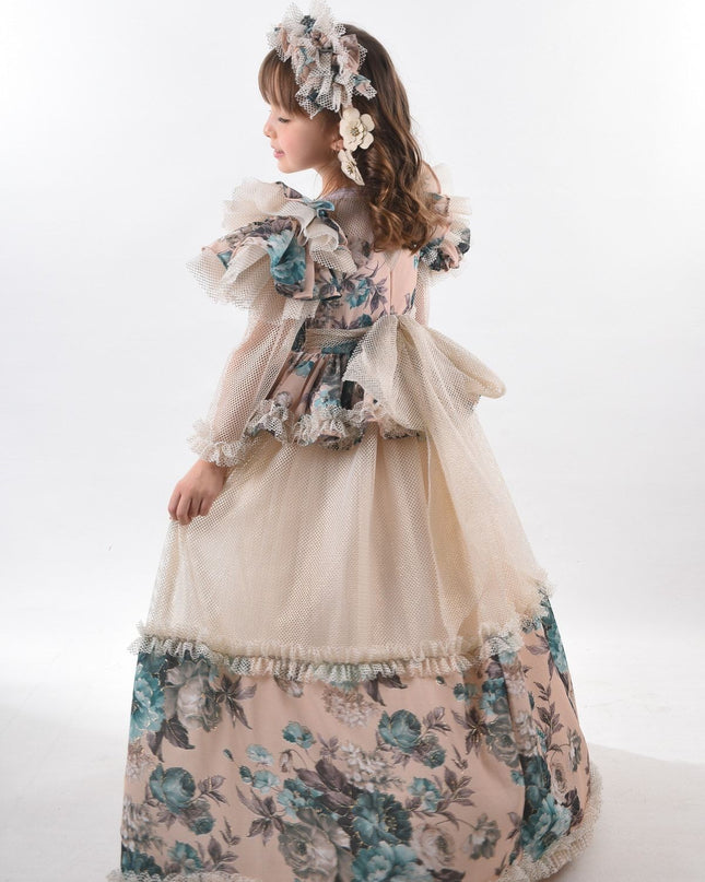 Kız çocuk vintage abiye elbise, krem tül üstü ve mavi çiçek desenli etekle, puf kollu tasarım, saç aksesuarıyla yan pozda